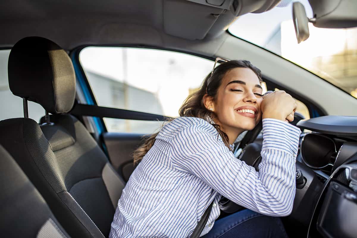 Una conductora feliz en su auto recién asegurado